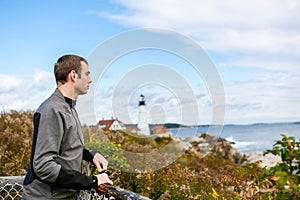 Man tourist looking away. At the background the Portland Headlight Lighthouse