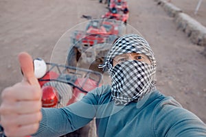 Man tourist make selfie photo on quad bike ATV safari in desert Sharm Hurghada, Egypt
