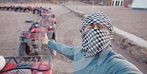 Man tourist make selfie photo on quad bike ATV safari in desert Sharm Hurghada, Egypt