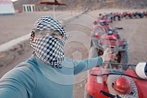 Man tourist make selfie photo on quad bike ATV safari in desert Sharm Hurghada, Egypt