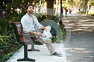 Man, tourist and map on bench in park outdoor for travel, direction or location for explore in nature. Person