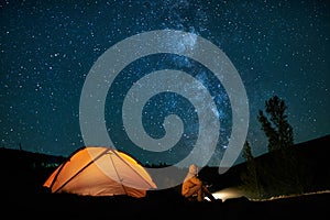 Man tourist near his camp tent at night.