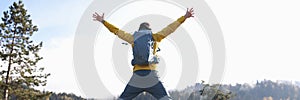 Man tourist with open arms jumping, lake and mountains on background