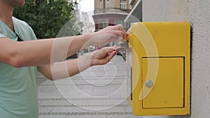 Man tourist sending letter into a yellow street mailbox. Male drops a postcard in a postbox. Postcrossing hobby concept