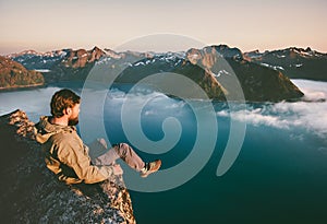 Man tourist sitting alone on the edge cliff mountains above sea