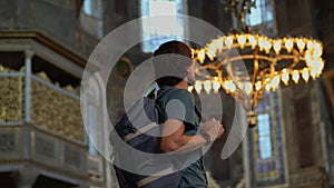 A man tourist stands in awe within the hallowed beauty of Istanbul's Ayasofya, immersed in the temple's majestic