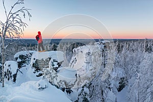 Man tourist stands over the winter cliff and looks