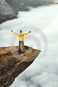 Man tourist success raised hands on Trolltunga rocky cliff edge in Norway