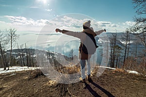 Man tourist traveler stands on a mountain and looks at the beautiful view of lake Baikal. Winter landscape