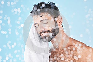 Man, towel with cleaning face and beauty, bokeh overlay with hygiene and grooming against blue background. Skincare