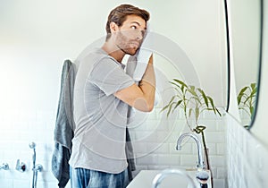 Man, towel and face for cleaning in bathroom, mirror and morning skincare routine for shower at home. Young guy with