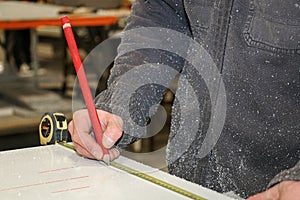 A man traces measurements on a PVC door frame in a carpentry. photo