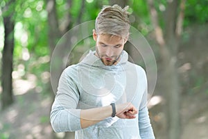 Man tracking fitness results dressed in sportswear outdoor. Man runner with fitness gadget. Smartwatch for fitness