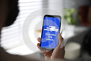 Man tracking parcel via smartphone indoors, closeup