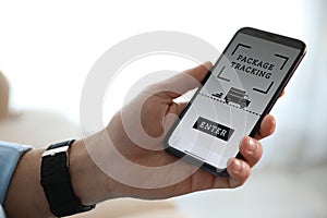 Man tracking parcel via smartphone indoors, closeup