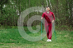 A man in a tracksuit is engaged in Nordic walking. The concept of a healthy lifestyle, cardio training. Copyspace