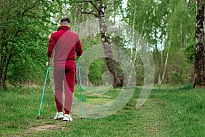 A man in a tracksuit is engaged in Nordic walking. The concept of a healthy lifestyle, cardio training. Copyspace