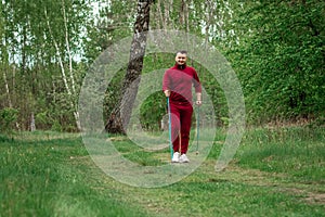 A man in a tracksuit is engaged in Nordic walking. The concept of a healthy lifestyle, cardio training. Copyspace