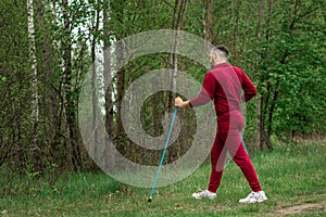 A man in a tracksuit is engaged in Nordic walking. The concept of a healthy lifestyle, cardio training. Copyspace