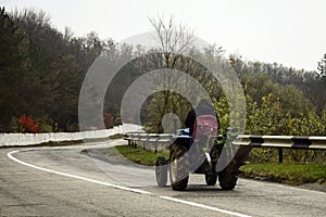 Man on tractor climbs mountain asphalt road