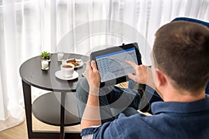 Man trading digital currencies online while relaxing by the cup of coffee in expencive hotel room