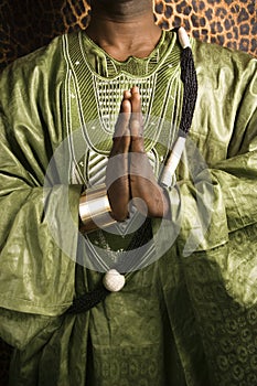 Man in traditional African clothing with hands together.