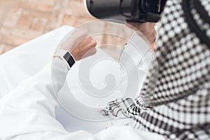 A man in traditional Arabic clothes thobe looks at his wristwatch. photo