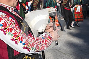 A man in a traditional Bulgarian costume plays an ancient musical folk wind instrument - bagpipes in Plovdiv, Bulgaria