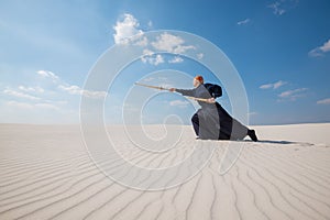 Man in traditional Japanese clothes makes a deep lunge with a sh