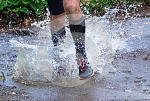 Man trail running in the mountains, crossing a creek photo