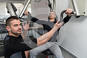 Man Train Chest On Machine With Personal Trainer