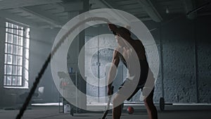 Man training with battle ropes in gym. Athlete doing intensity fitness workout