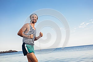 Man training on the beach in morning. Young man on morning run outdoors