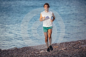 Man training on the beach in morning. Young man on morning run outdoors