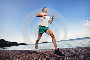 Man training on the beach in morning. Young man on morning run outdoors