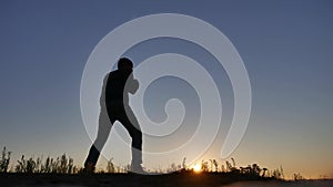 Man is training doing an imitation boxing shadow lifestyle fight. Martial arts concept. Silhouette man on a hill nature