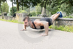 Man training and exercising doing push ups in the park.