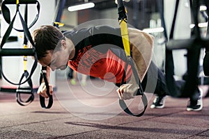 Man training with fitness straps in the gym.