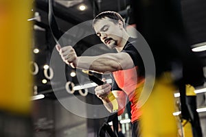 Man training with fitness straps in the gym.