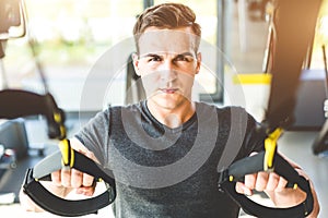 Man training with fitness straps in the gym. Sportsman exercising her muscles sling or suspension straps.