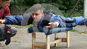 Man is training before flying in air tube in special costume lying on bench.