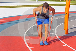 Man is training his hands and back with elastic bands. Guy exercising with rubber stepping on a rubber band. Fit, fitness,