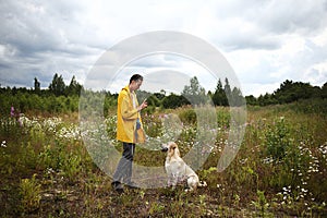 Man training Labrador Retriever on green meadow