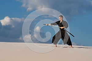 Man training martial arts, iaido, in desert