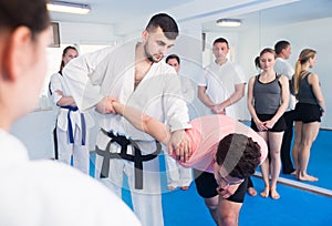 man training new taekwondo holds with adults during class