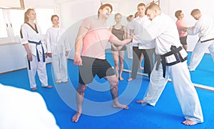 Man training new taekwondo holds with adults during class