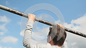 Man training outdoors, making pull up on horizontal fitness bar. Sport activities. Active sport. Male pulling up on bar