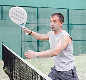 Man training to play tennis on the padel court outdoor. Athletes training in background