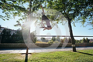 Man Training With Trickline Slackline In City Park