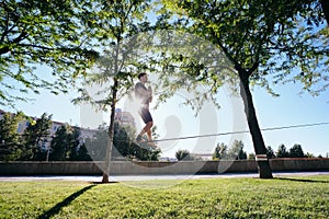 Man Training With Trickline Slackline In City Park